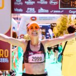 Une femme passe la ligne d'arrivée d'un marathon avec le sourire - effort - motivation - succès - coaching