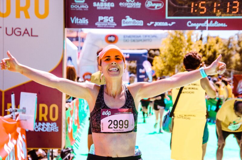 Une femme passe la ligne d'arrivée d'un marathon avec le sourire - effort - motivation - succès - coaching