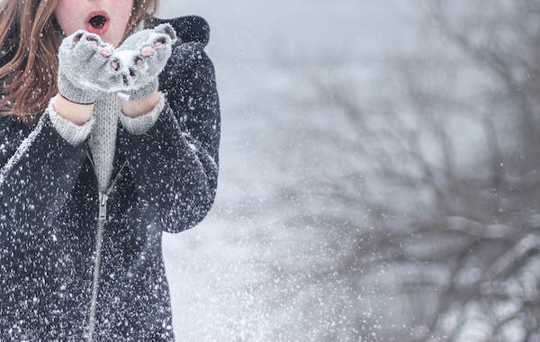 Une jeune femme souffle sur de la neige qu'elle avait dans ses mains gantées. Apprenez à mieux vivre les passages à vide.