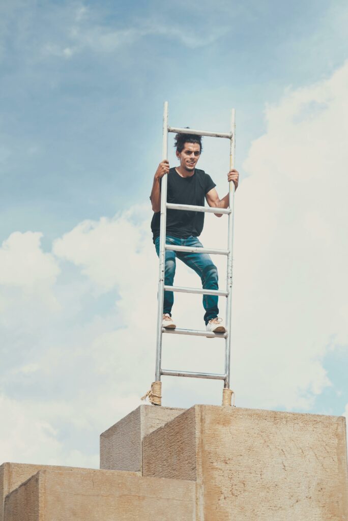 Un homme monte sur une échelle en équilibre en haut d'un édifice. Une bonne estime de soi est le meilleur moyen de réguler ses variations émotionnelles.