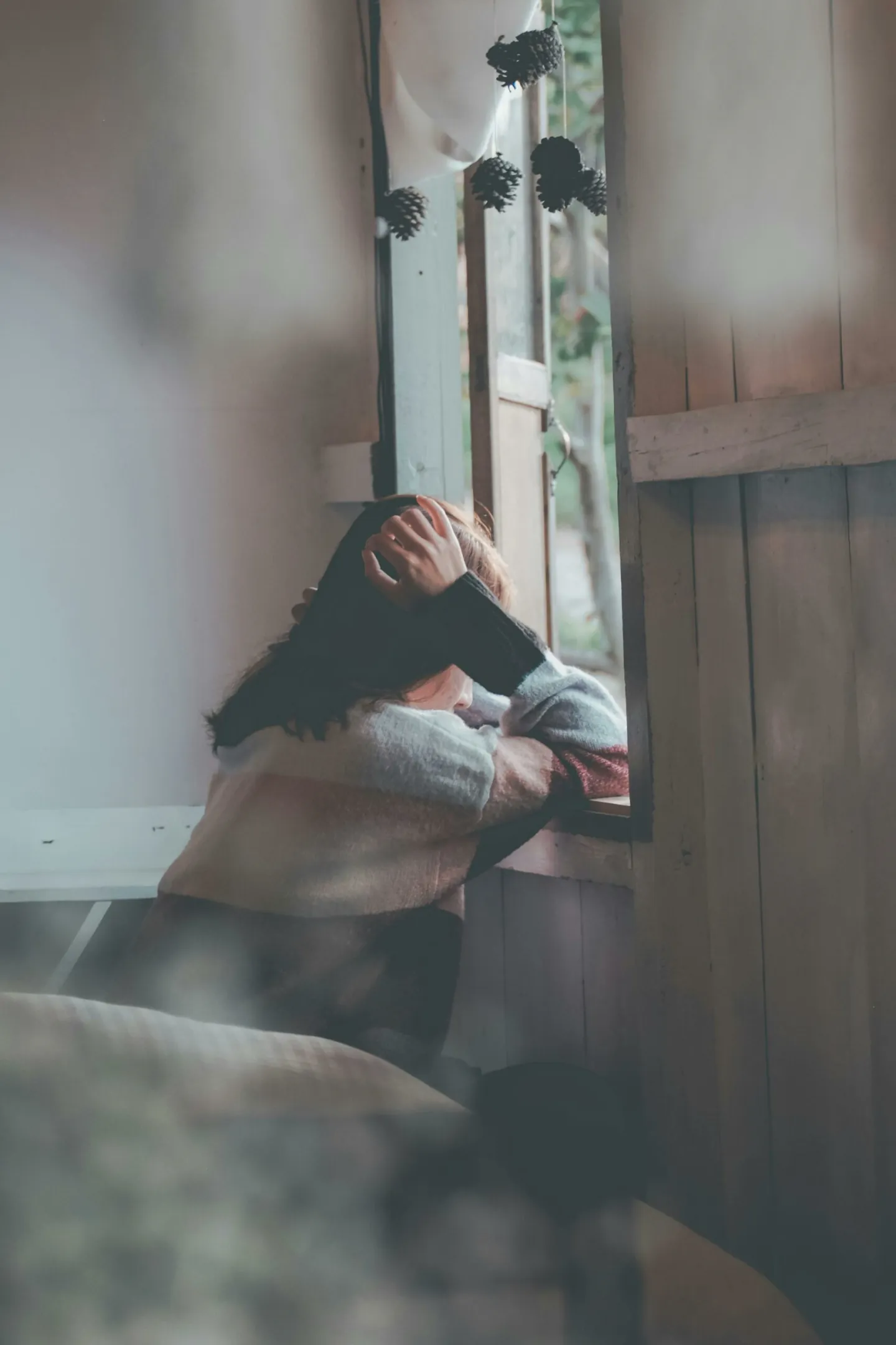 Une jeune femme accoudée à une fenêtre ouverte se tient la tête dans les mains - revenir au premier plan de sa vie - mieux se connaitre - jouer le premier rôle de sa vie - coaching de vie - Sylvie Rauwel - Nantes