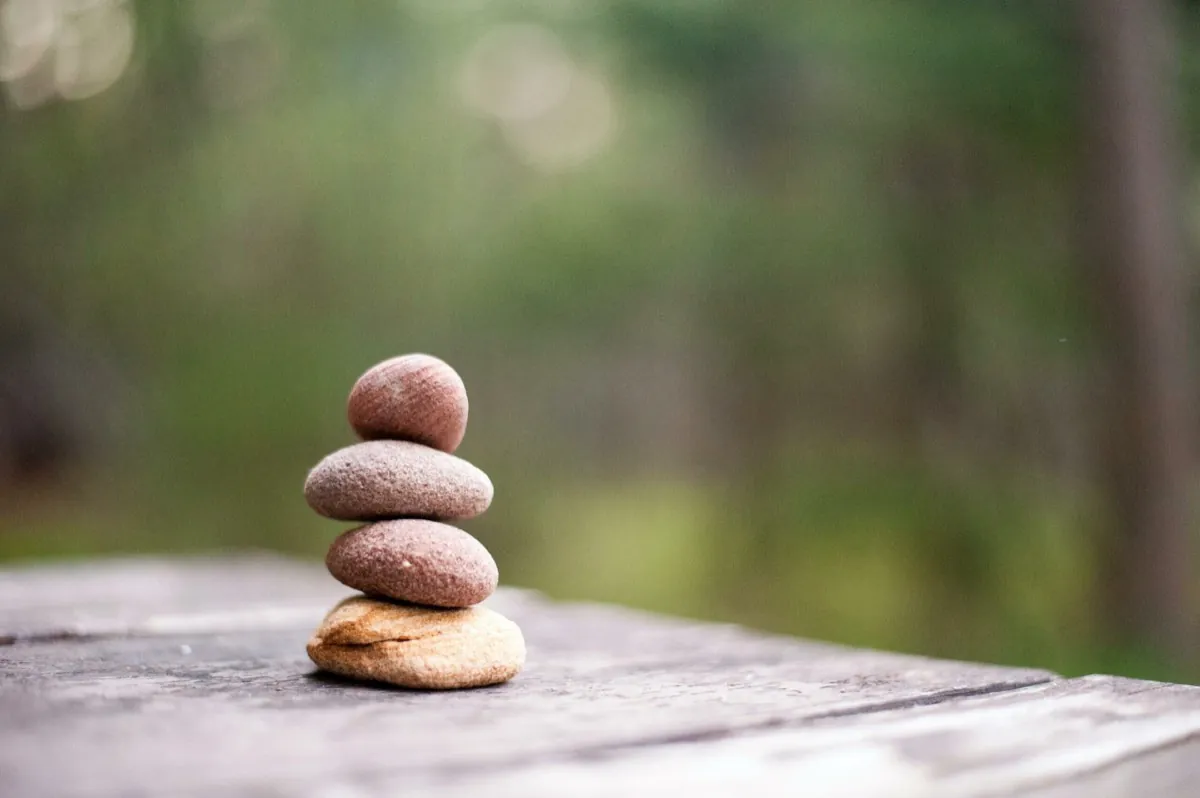 Photo de 4 galets empilés en équilibre sur une table en bois - Hypnorelaxation une combinaison bien-être - Hypnose - Relaxation - Libérer le corps et l'esprit
