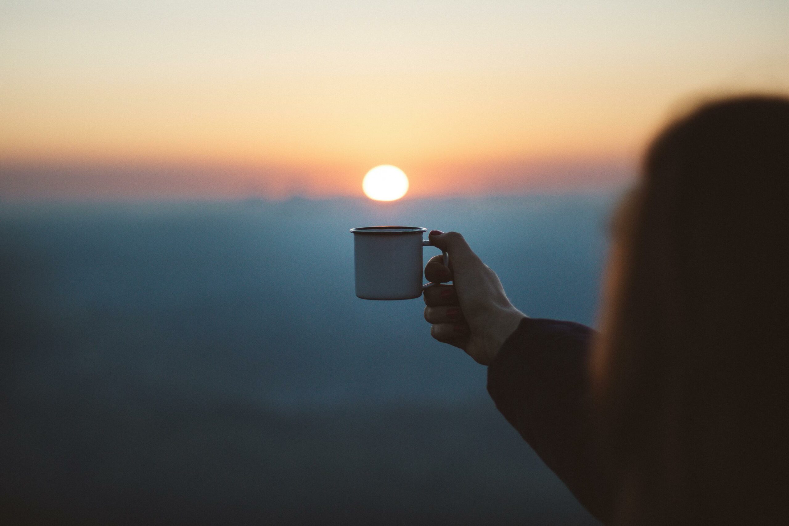 Quelqu'un tient une tasse semblant pouvoir recevoir le soleil couchant - Comment prévenir la dépression hivernale ? - Hypnose et coaching de vie