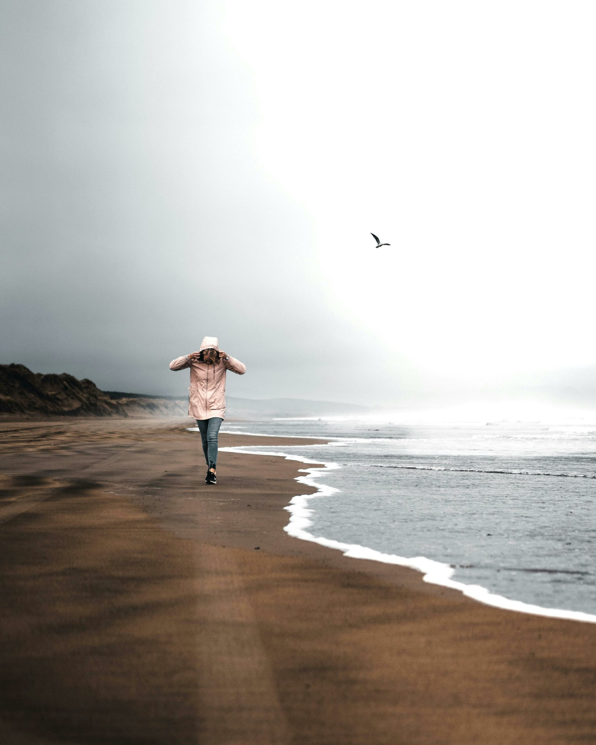 Une femme marche sur une plage en hiver - Comment prévenir la dépression hivernale ? - Hypnose et coaching de vie