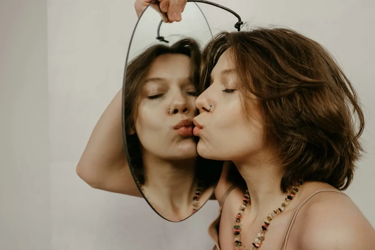 Une femme, les yeux fermés, embrasse le miroir qui montre son reflet - Image de soi - Améliorer son estime de soi
