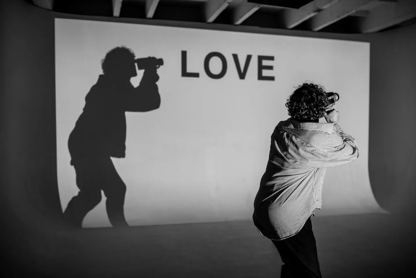 L'ombre d'un homme de dos vise le mot Love avec sa caméra - Amour de soi - Coaching de vie - Sylvie Rauwel - Nantes